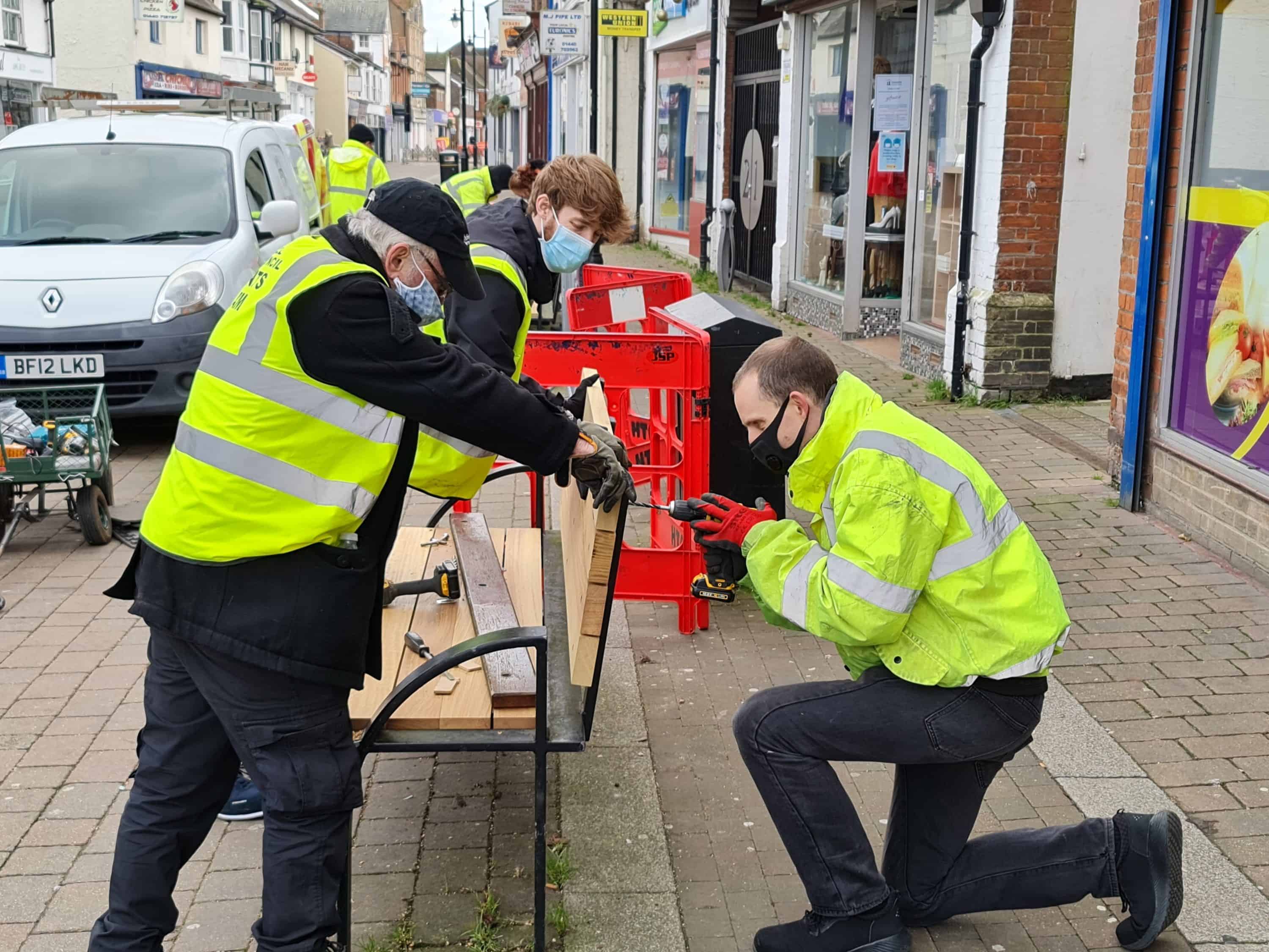 staff replacing the wood on an old bench